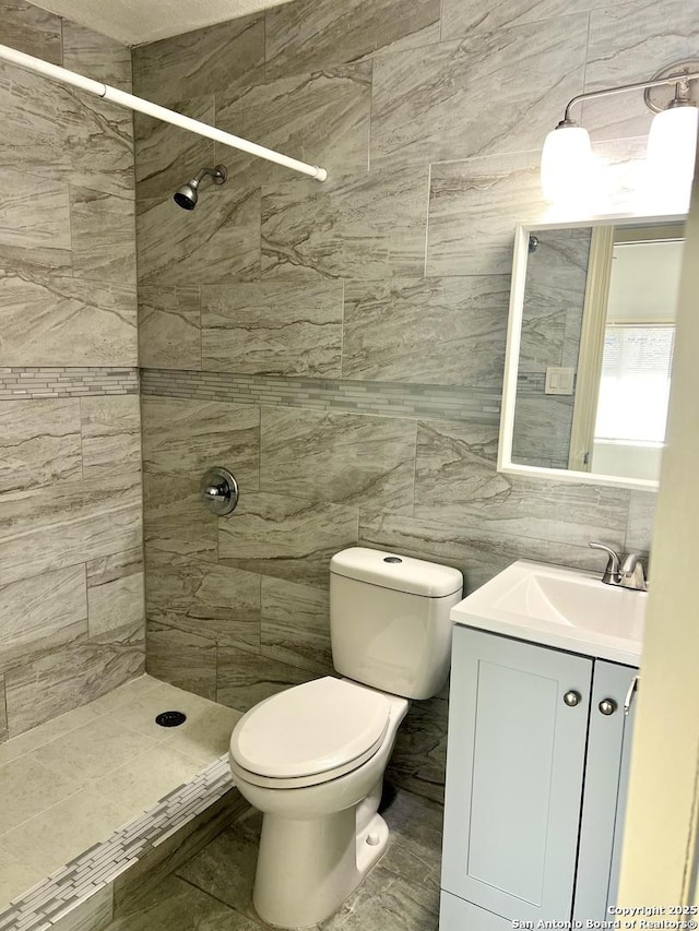 bathroom featuring toilet, vanity, tile walls, and tiled shower