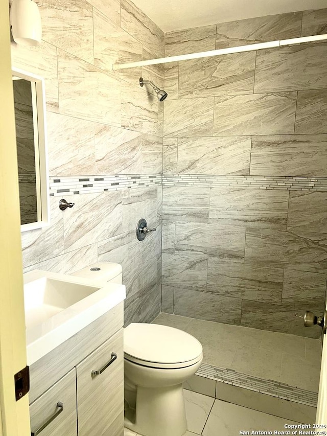 bathroom with toilet, vanity, and tiled shower