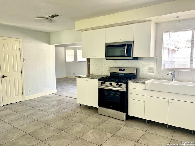 kitchen with plenty of natural light, stainless steel appliances, white cabinets, and sink