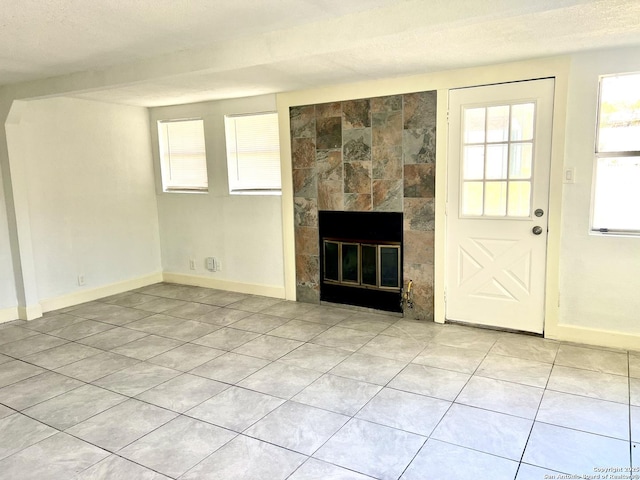 unfurnished living room featuring a textured ceiling, a tile fireplace, and light tile patterned flooring