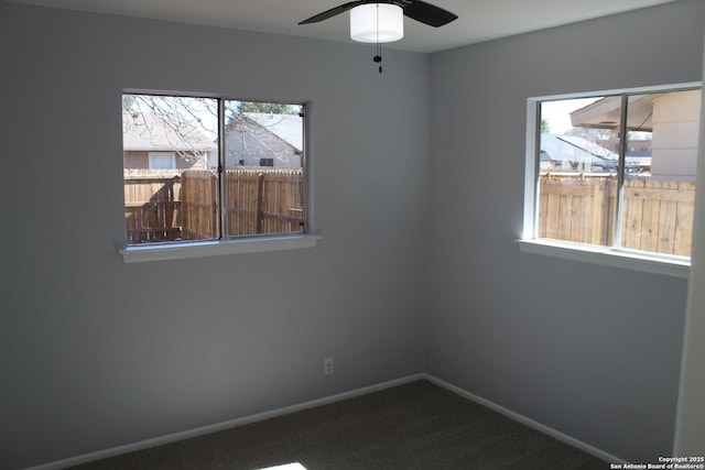 carpeted spare room featuring ceiling fan and plenty of natural light