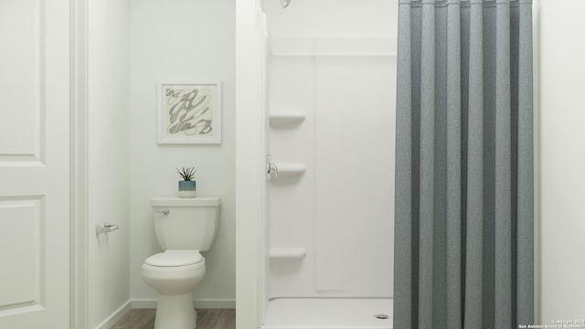 bathroom with hardwood / wood-style flooring, toilet, and walk in shower