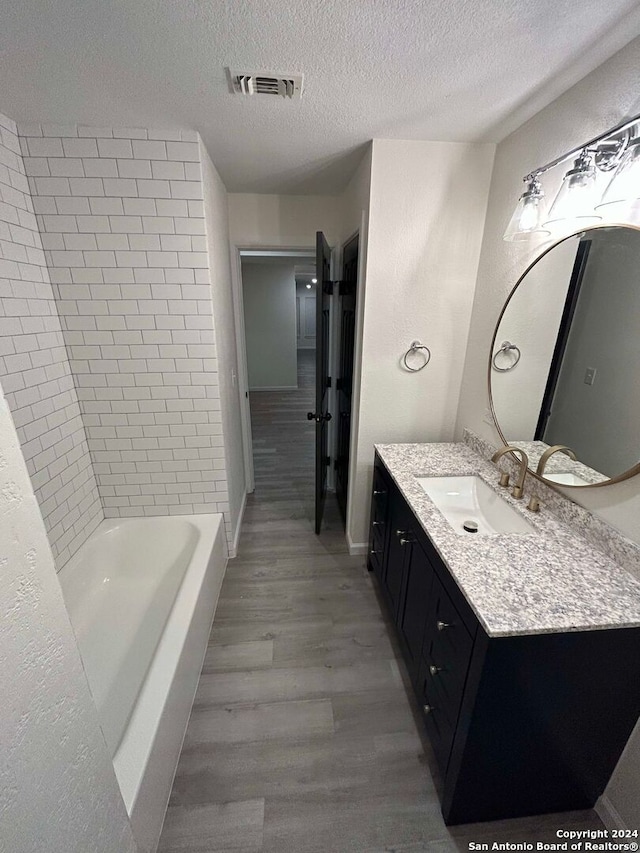 bathroom with hardwood / wood-style flooring, a textured ceiling, and vanity