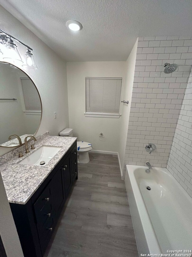 full bathroom with toilet, vanity, tiled shower / bath, hardwood / wood-style flooring, and a textured ceiling