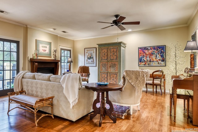 living room with ornamental molding, ceiling fan, and light hardwood / wood-style flooring