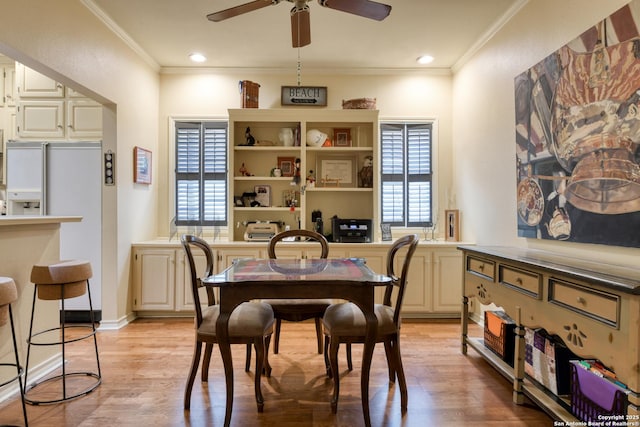 dining room with ceiling fan, ornamental molding, and light wood-type flooring