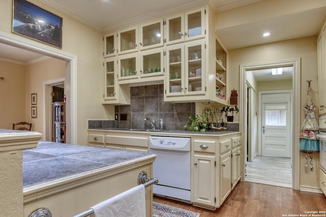 kitchen with sink, dishwasher, ornamental molding, decorative backsplash, and light wood-type flooring