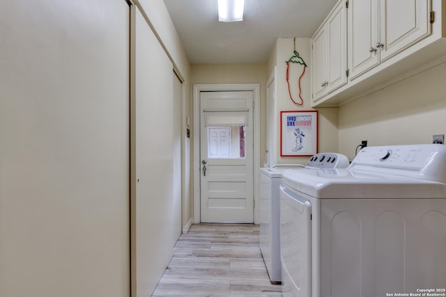 laundry room featuring washer and dryer, light hardwood / wood-style flooring, and cabinets