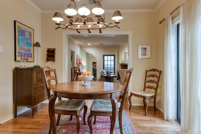 dining space featuring hardwood / wood-style flooring, crown molding, and an inviting chandelier