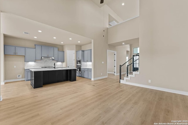 kitchen featuring light wood-style floors, open floor plan, light countertops, and a center island with sink