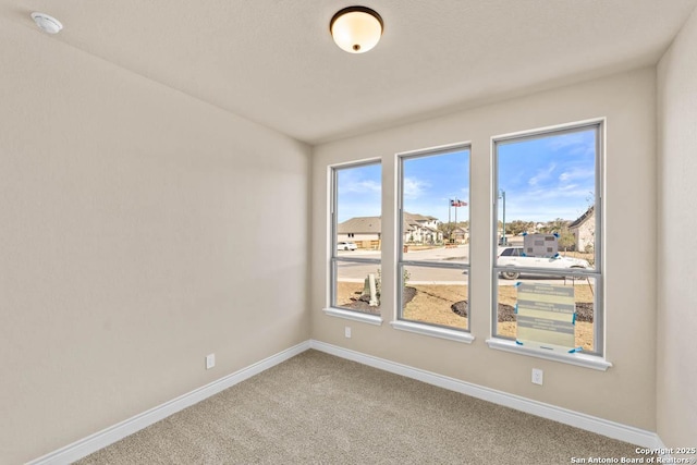 spare room with baseboards, a healthy amount of sunlight, and carpet flooring