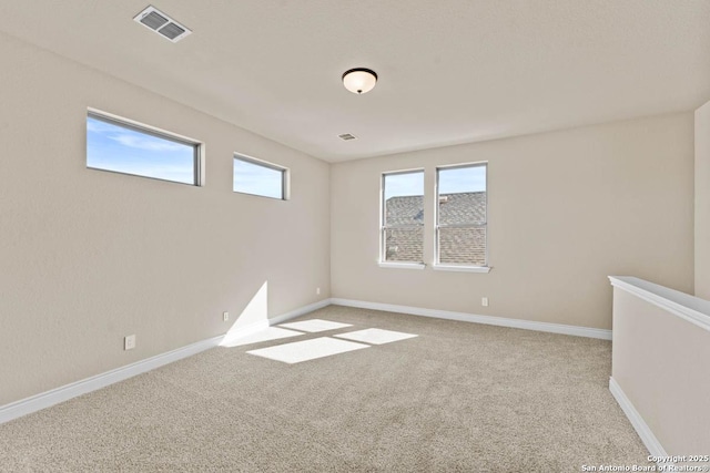 empty room featuring light colored carpet, visible vents, and baseboards