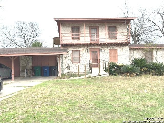 view of front of home with a balcony, a front lawn, and a carport