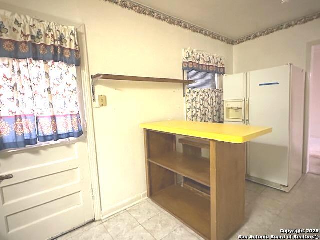 kitchen with light tile patterned floors and white refrigerator with ice dispenser