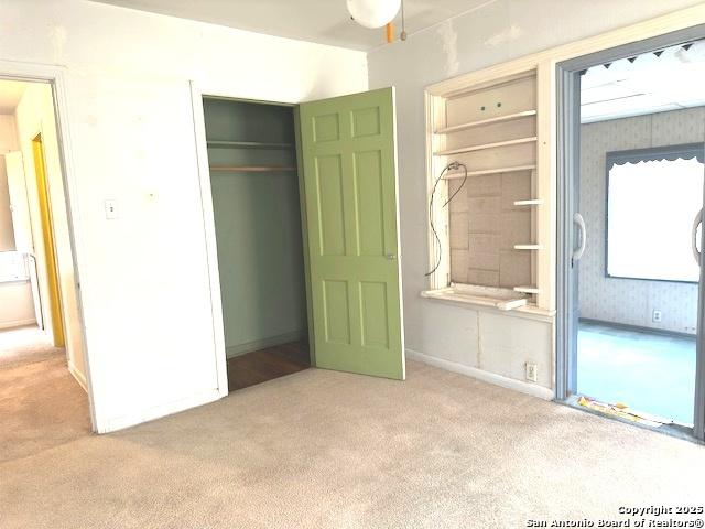 unfurnished bedroom featuring light carpet, a closet, and ensuite bathroom