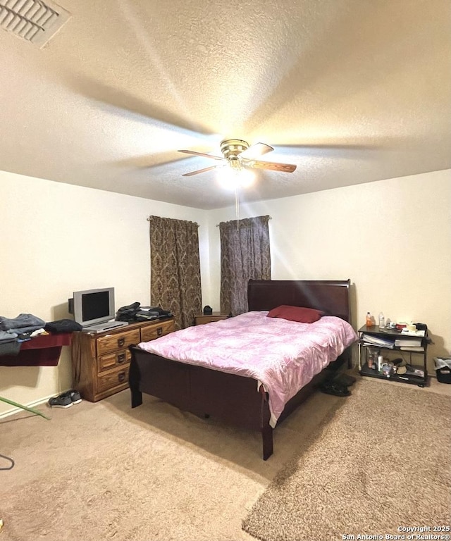 bedroom with a textured ceiling, ceiling fan, and light colored carpet