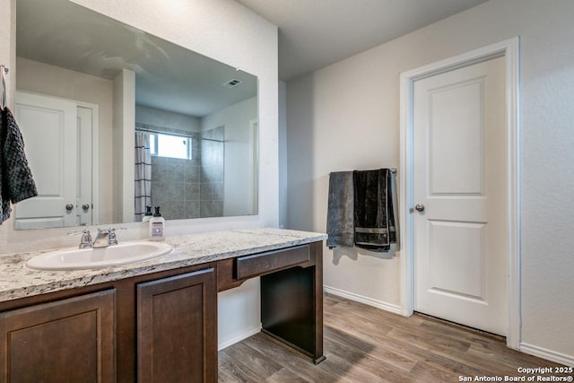 bathroom featuring vanity, tiled shower, and hardwood / wood-style flooring