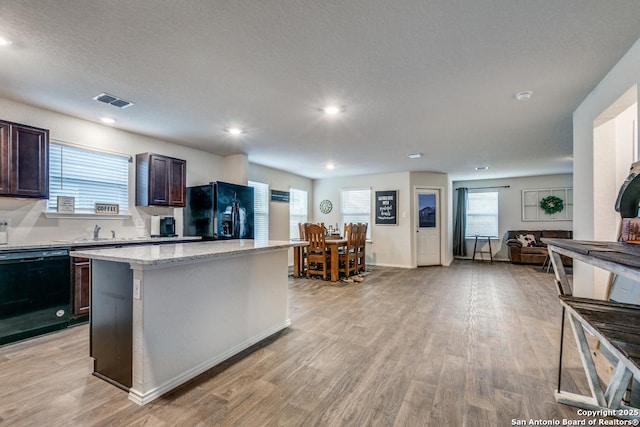 kitchen with light hardwood / wood-style floors, black appliances, a center island, dark brown cabinetry, and a healthy amount of sunlight