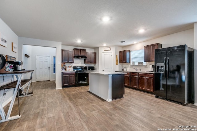 kitchen featuring light hardwood / wood-style floors, black appliances, a center island, dark brown cabinetry, and a textured ceiling