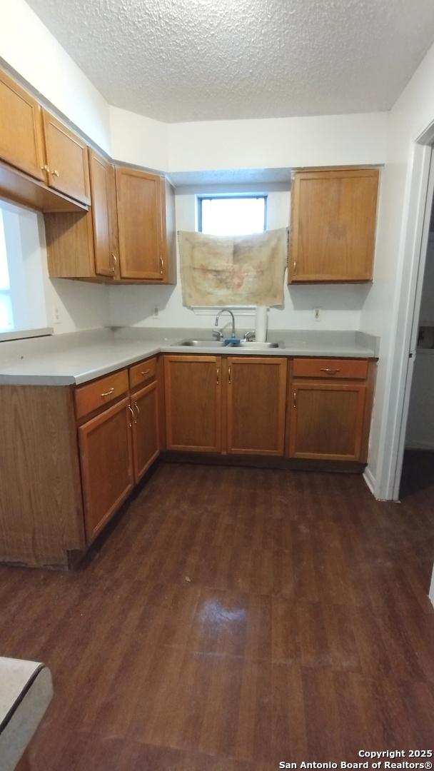 kitchen with dark wood-type flooring, sink, and a textured ceiling