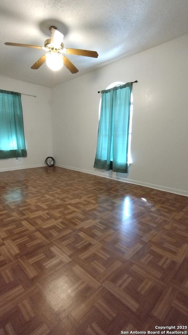 unfurnished room featuring ceiling fan, a textured ceiling, and dark parquet floors