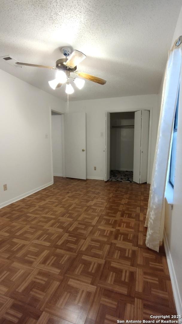 unfurnished bedroom with ceiling fan, dark parquet floors, and a textured ceiling