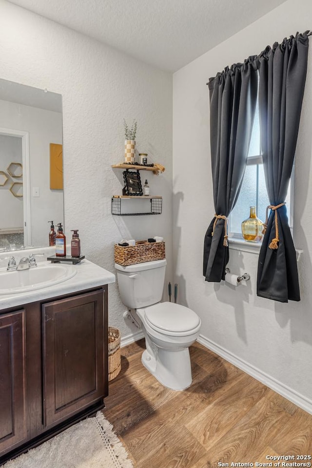 bathroom with hardwood / wood-style flooring, a textured ceiling, toilet, and vanity