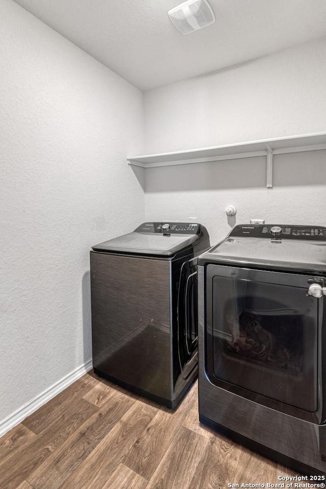 clothes washing area featuring wood-type flooring and washer and dryer