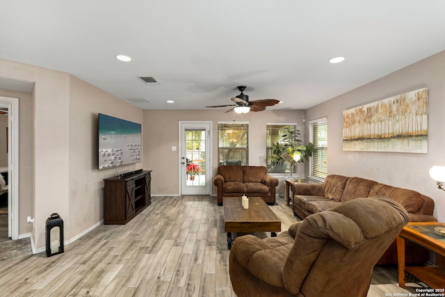 living room featuring ceiling fan, light wood-type flooring, and a wealth of natural light