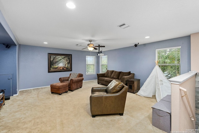 living room featuring ceiling fan, plenty of natural light, and light carpet