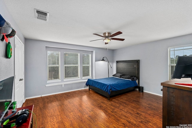 bedroom with ceiling fan, dark hardwood / wood-style flooring, and a textured ceiling