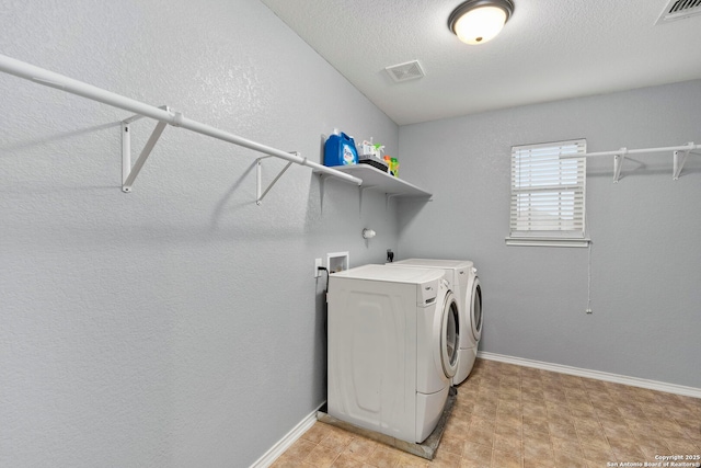 laundry area with washing machine and clothes dryer and a textured ceiling