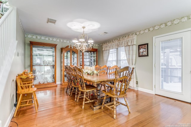 dining space with light wood-type flooring and a notable chandelier