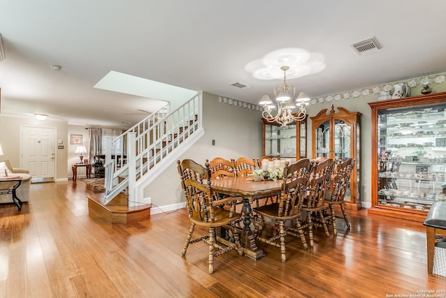 dining space featuring wood-type flooring and a notable chandelier