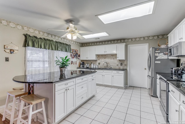 kitchen featuring black range with electric cooktop, white cabinetry, dark stone counters, and sink