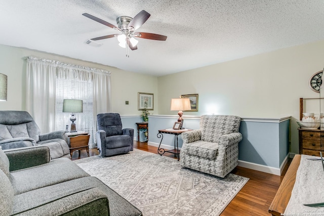 living room with ceiling fan, wood-type flooring, and a textured ceiling