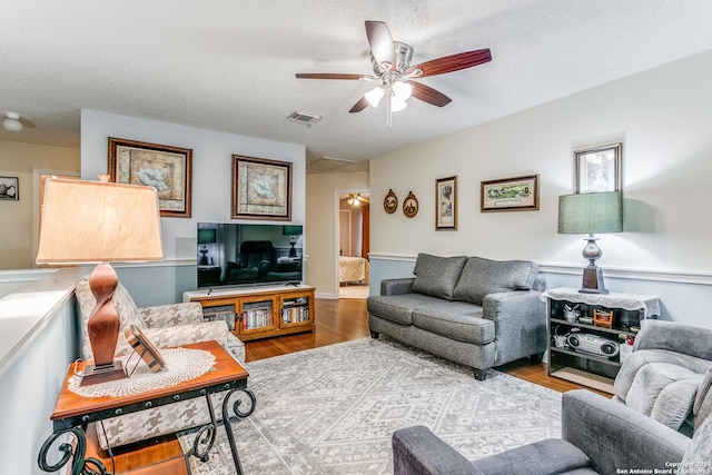 living room with ceiling fan, a textured ceiling, and hardwood / wood-style floors