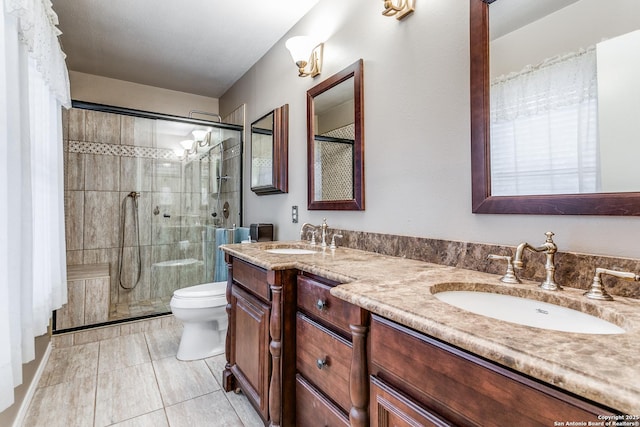 bathroom with toilet, tile patterned flooring, a shower with shower door, and vanity