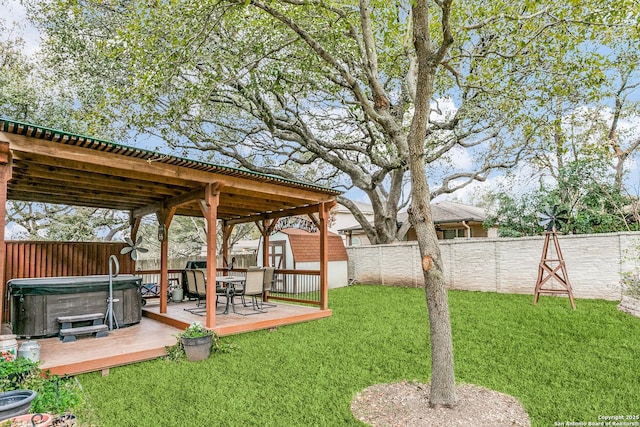 view of yard featuring a wooden deck, a hot tub, and a storage shed