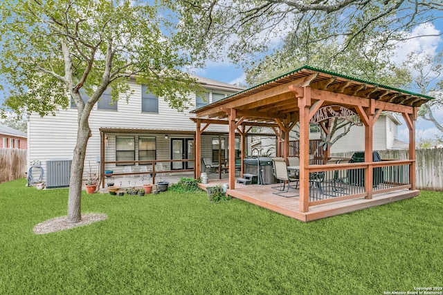 back of property featuring central AC, a wooden deck, a hot tub, and a yard