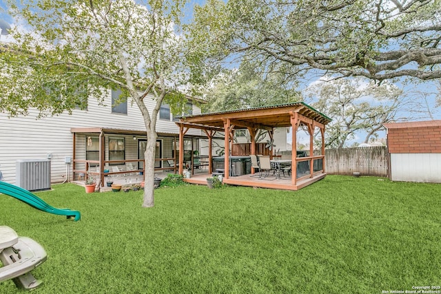 rear view of house featuring central AC unit, a wooden deck, a storage unit, and a lawn