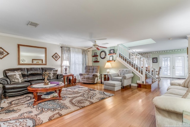 living room with ceiling fan, hardwood / wood-style floors, a skylight, ornamental molding, and french doors