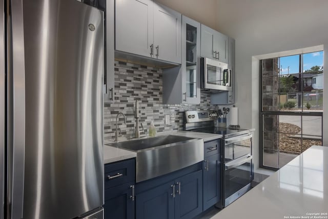 kitchen with white cabinetry, stainless steel appliances, tasteful backsplash, blue cabinetry, and sink