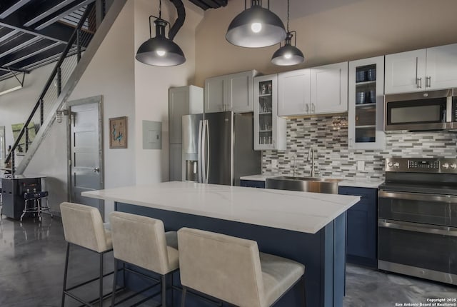 kitchen with sink, stainless steel appliances, a kitchen island, and pendant lighting