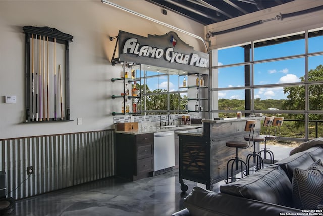 bar with sink, a wealth of natural light, stainless steel dishwasher, and tasteful backsplash