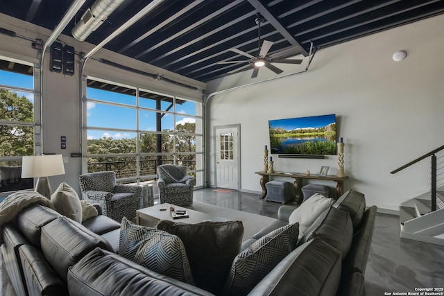 living room featuring a towering ceiling, concrete flooring, and ceiling fan