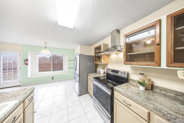 kitchen featuring appliances with stainless steel finishes, decorative light fixtures, a textured ceiling, wall chimney exhaust hood, and cream cabinets