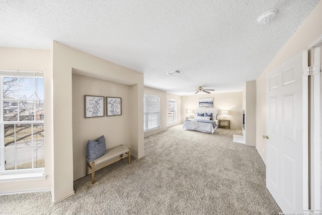 unfurnished bedroom featuring ceiling fan, multiple windows, a textured ceiling, and carpet flooring