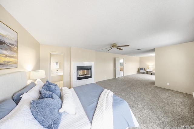 carpeted bedroom featuring a textured ceiling, ceiling fan, a tiled fireplace, and ensuite bath