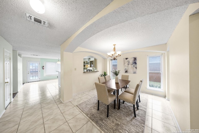 dining area with light tile patterned floors, a wealth of natural light, and an inviting chandelier